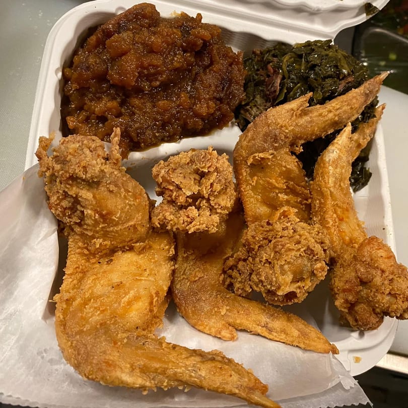 Dakari Soul Food's fried chicken wings, collard greens, and candied yams in a takeout container.